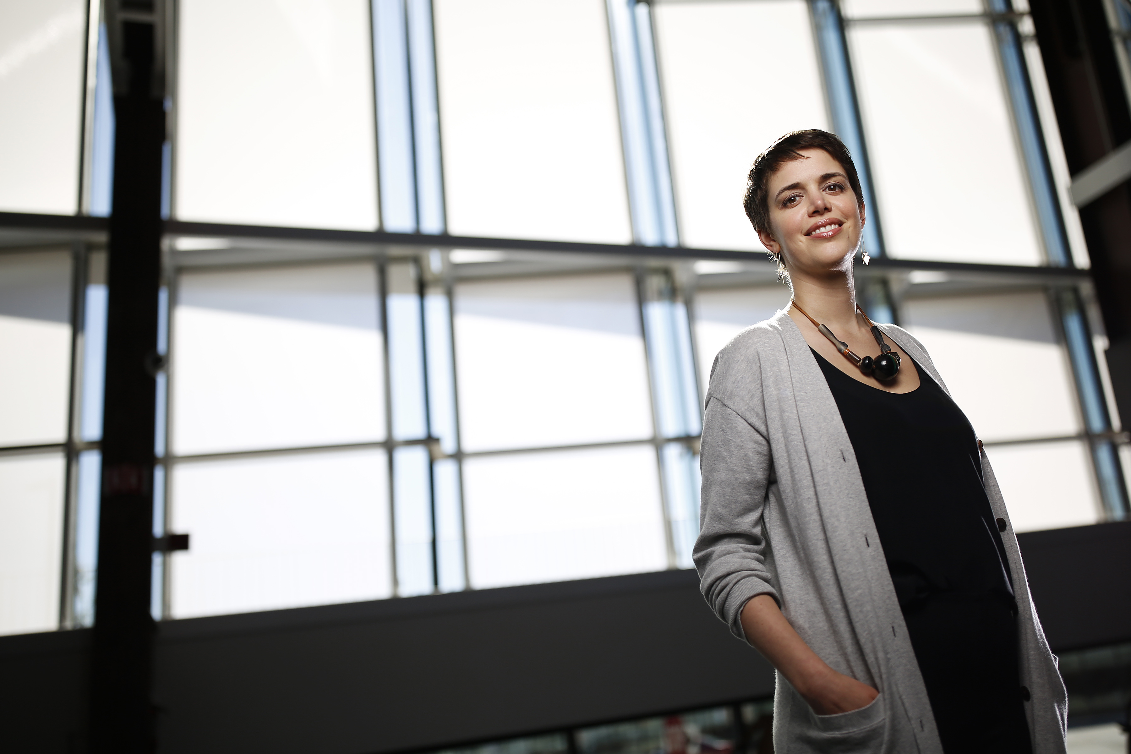 Brooks Bell standing in front of large windows, confident and smiling